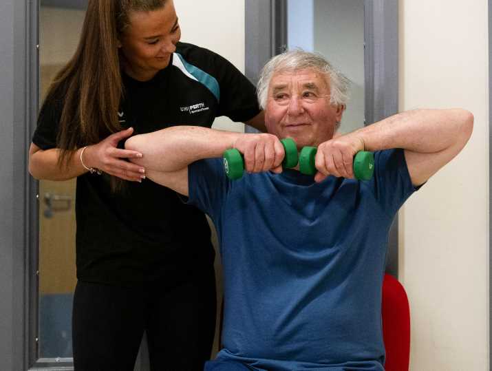 Amy assists her grandad, James, to perform a Strength and Balance movement.