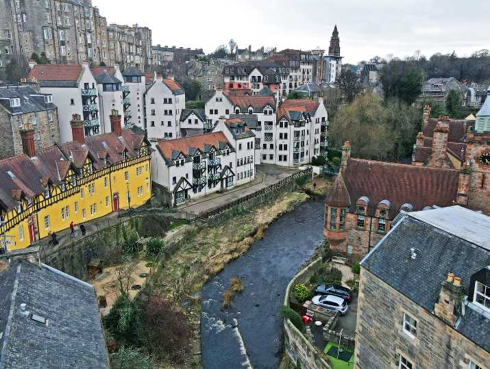 An aerial shot of Dean Village in Edinburgh, with old, picturesque housing sprawling from the left around to the right above a river.