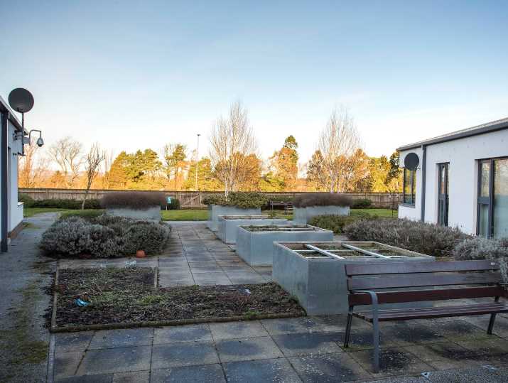 A shared garden with planters and benches on a hospital ground.