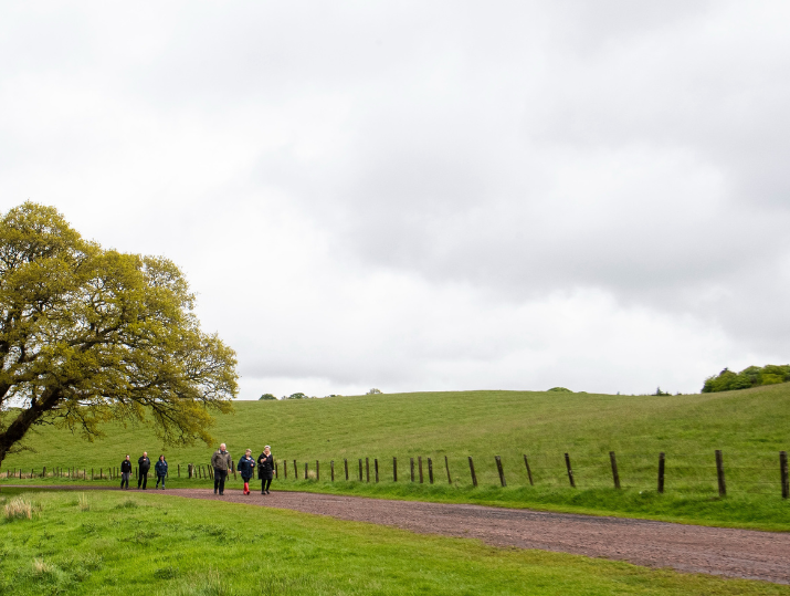 A group of walkers talk as they walk along a country path as part of a Healthy Valleys Health Walk.